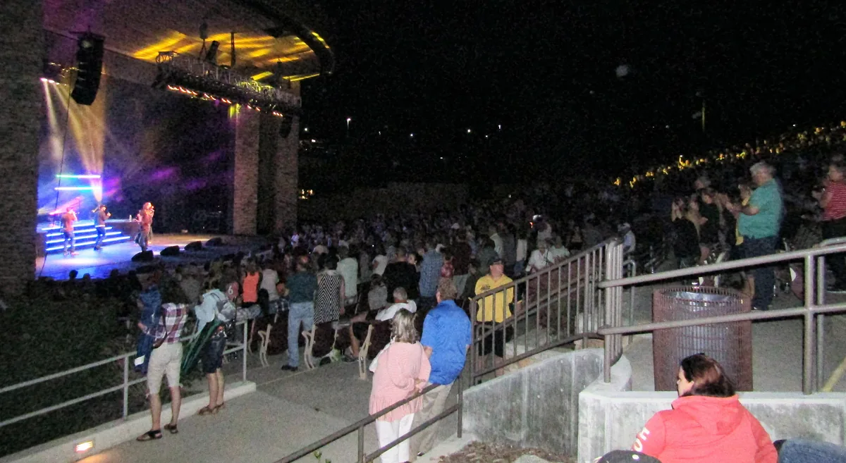 A crowd of fans with raised hands at a live concert