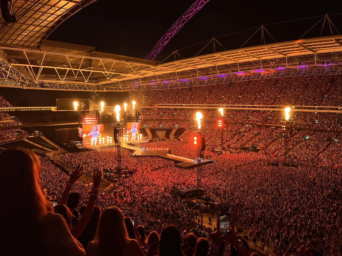 Taylor Swift performing with a guitar on a brightly lit stage